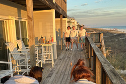 Hier sieht man fünf Personen, die Flunky Ball spielen bei Sonnenschein auf einem Balkon am Meer. 